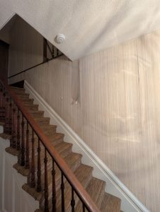 Stairway walls with original wallpaper before removal in historic farmhouse