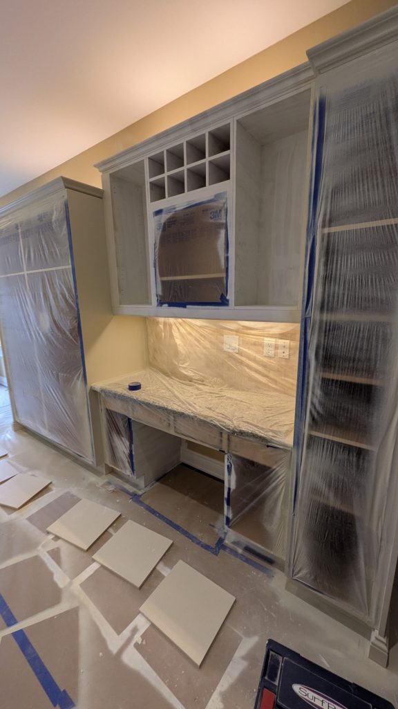 Kitchen cabinet preparation with masking and surface protection before cabinet refinishing in Ancaster, Ontario.