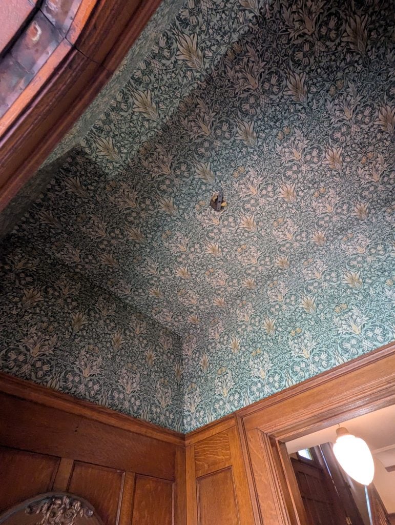 Professional wallpaper installation in a Hamilton home featuring patterned wallpaper with original wood trim.