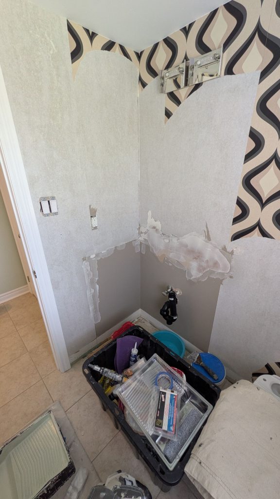 Wallpaper removal in Hamilton showing stubborn backing and wall repairs in a powder room.